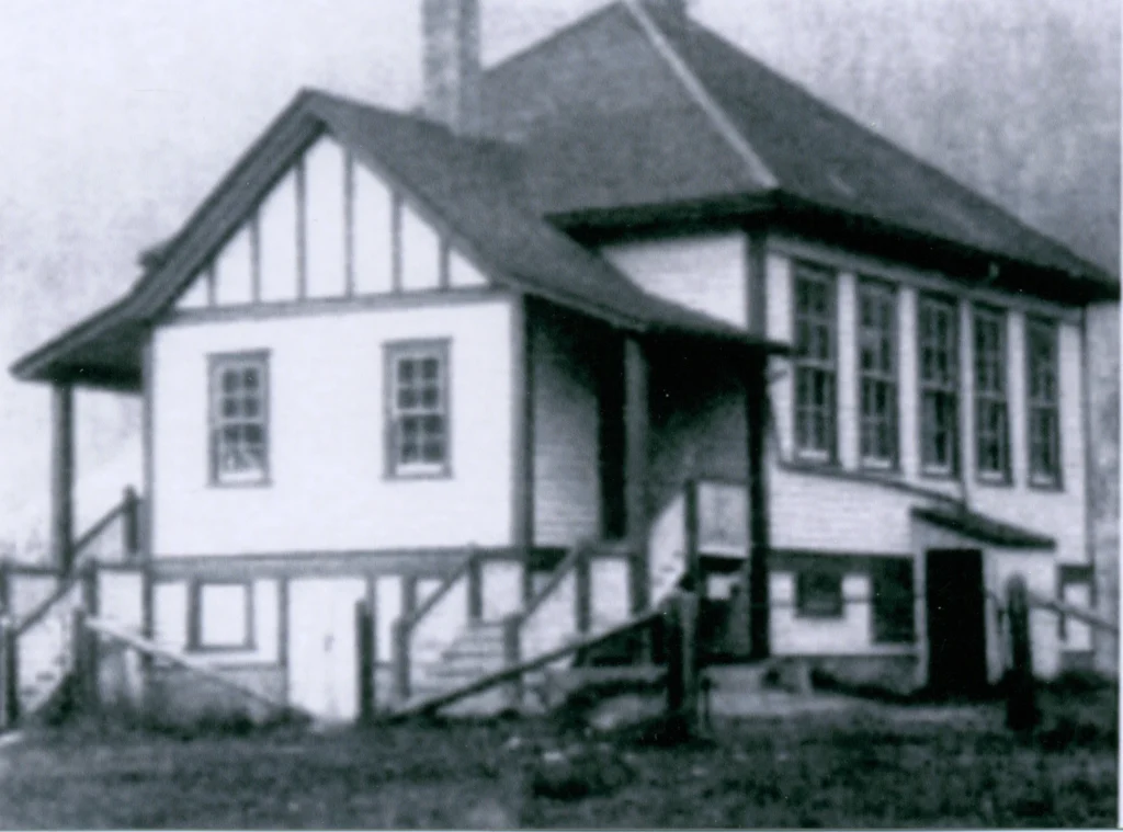 A grainy black and white photograph from 1914 of Robson School, depicting a two-story wooden building with a steep gabled roof and large windows, typical of early 20th-century educational structures, evoking the historic charm of the era's rural schoolhouses.