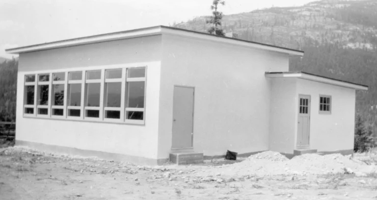 A black and white photograph from 1947 featuring the Gibson Creek School, a simple, single-story building with a prominent row of windows, captured in a rural setting with a mountainous backdrop, reflecting the educational architecture of the mid-20th century.