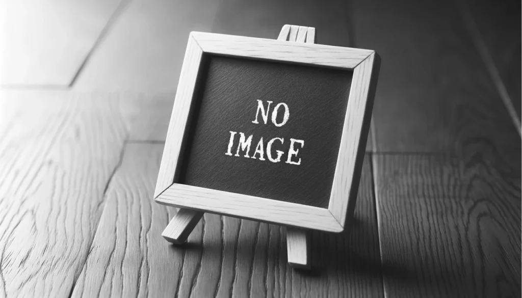 A black and white photograph featuring a miniature easel with a small blackboard inscribed with NO IMAGE in white letters standing on a wooden surface with a pronounced grain pattern. The image conveys a message about the absence of visual content.